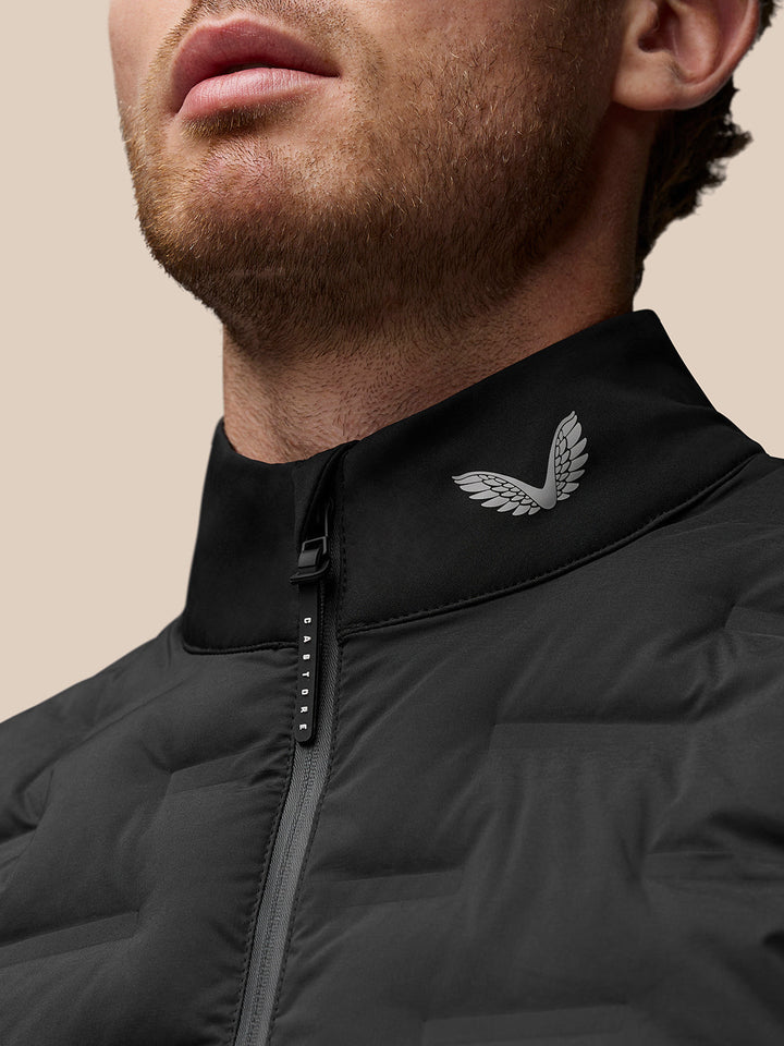 Close-up of black stand collar with a wing logo and Castore branded zipper pull