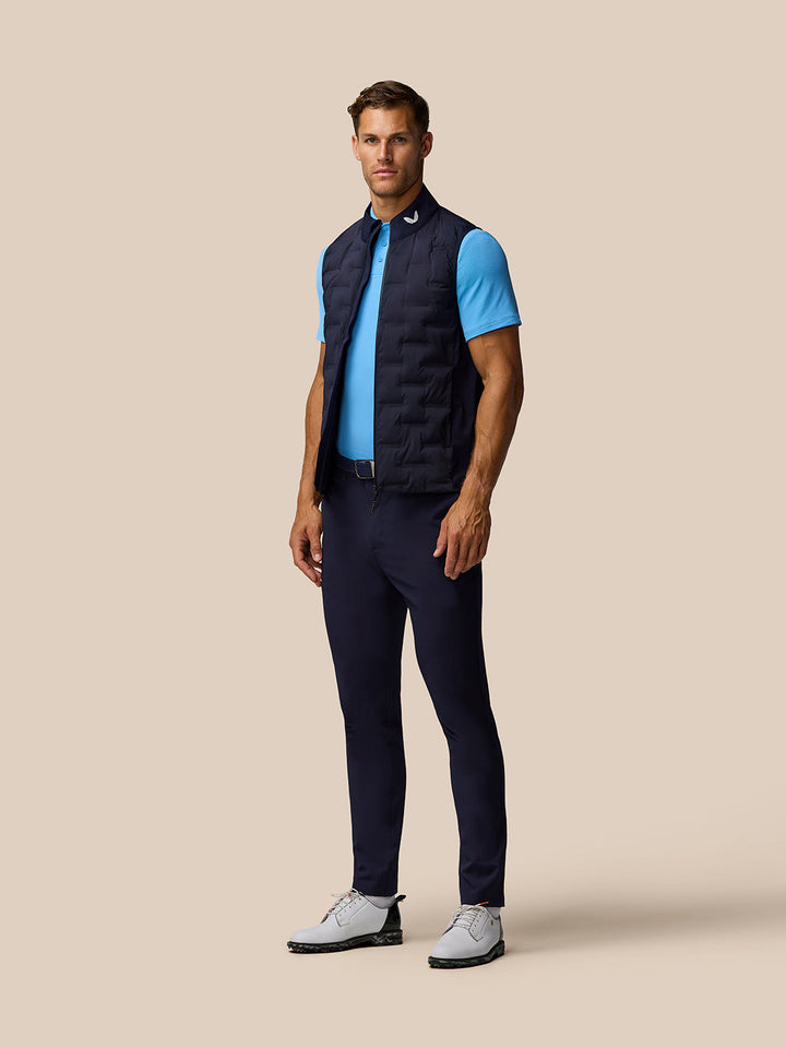 Side profile of a man in a navy quilted sleeveless golf gilet over a blue polo.