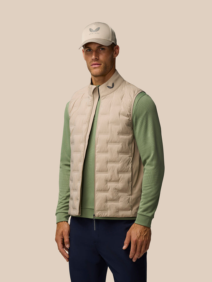 Beige mushroom Golf Pinnacle gilet with quilted front panel worn over a green top.