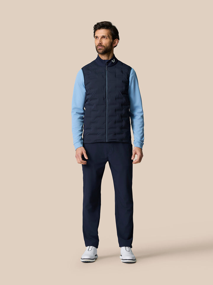 Male model wearing Golf Pinnacle Gilet in midnight navy with a light blue long sleeve layer