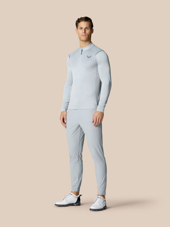 Male model wearing light grey Castore Golf Pinnacle 32 inch trousers with a matching top