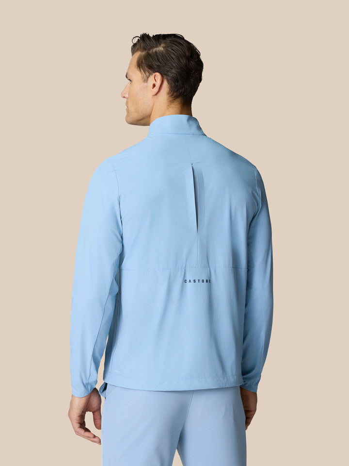 Back view of sky blue Golf Flex Jacket showing vertical back vent and Castore logo across lower back