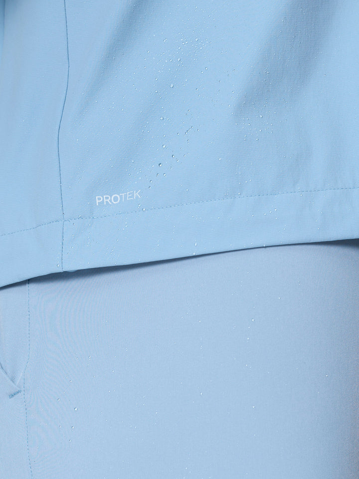 Close up of water droplets on sky blue Flex Jacket fabric with PROTEK logo