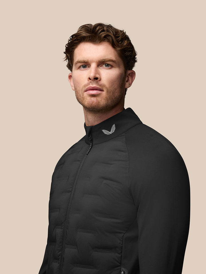 Male model wearing black Golf Pinnacle Jacket with stand collar and front zip.