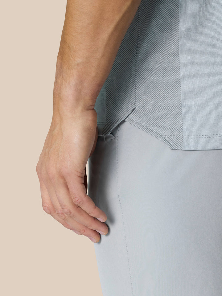 Close up of the light grey Pinnacle LVS Polo showing side vent panel and engineered knit detail