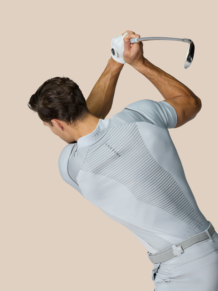 Male golfer in light grey Pinnacle LVS Polo mid swing, highlighting engineered knit and vent panels