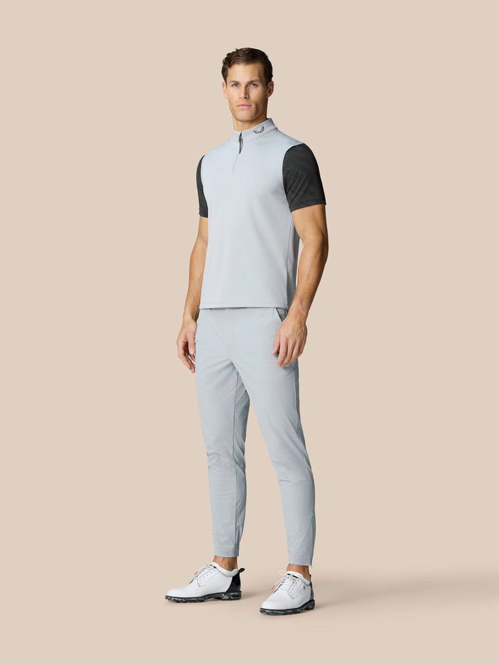 Male model wearing light grey golf gilet over a black mesh tee, full outfit shown.
