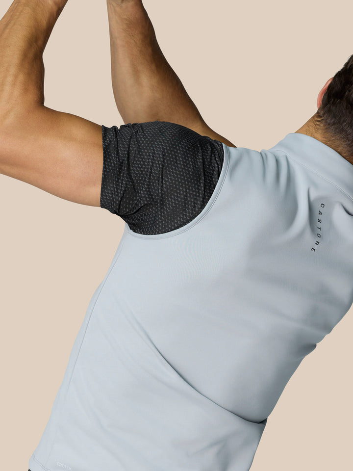 Model wearing light grey sleeveless golf gilet with high neck and 1/2 zip, featuring mesh underarm panel.