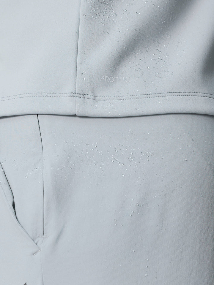 Close up of light grey golf gilet fabric showing water droplets and ProTek branding.