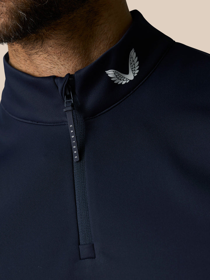 Close-up of navy gilet collar showing a zip and Castore wing logo at the neck