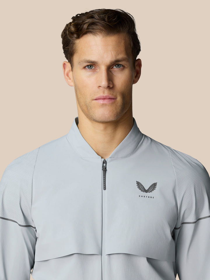 Male model wearing Golf Pinnacle LVS Woven Jacket in mid grey with front zipper and chest logo.