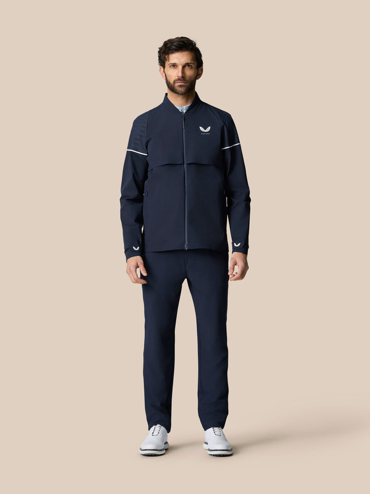 Male model wearing Golf Pinnacle LVS Woven Jacket in Midnight Navy, full-body front view.