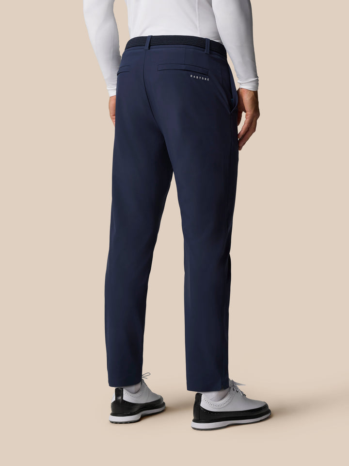 Back view of a man in navy golf trousers with a black belt and Castore logo on the back pocket