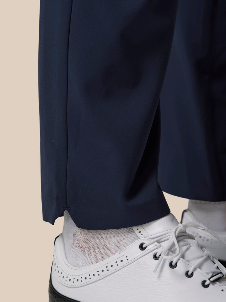 Close-up of navy golf winter trouser leg with a cuffed hem resting over a white golf shoe