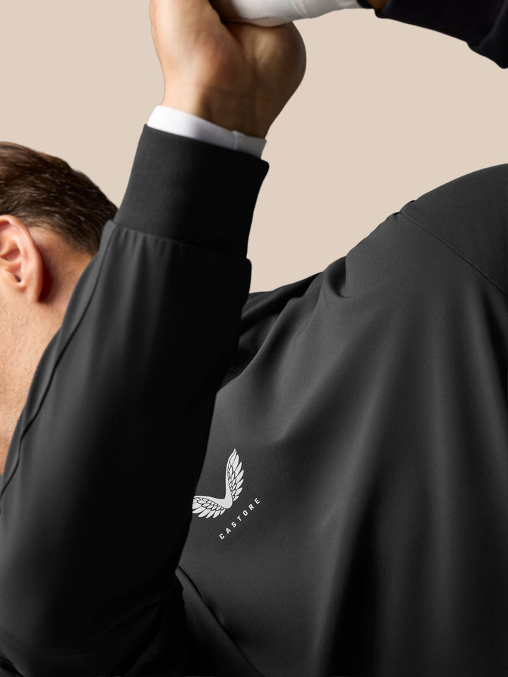 Close-up of a man wearing the black Golf Pinnacle Performance Hoodie showing the center chest logo.