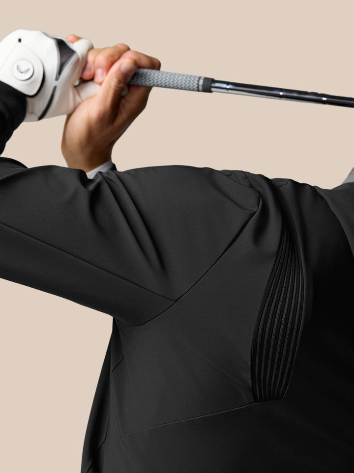Close up of a golfer gripping a club in a black Pinnacle Performance Hoodie showing textured sleeve panel