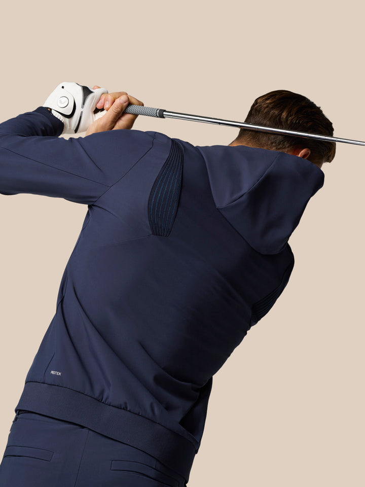 Back view of a golfer wearing the Midnight Navy Golf Pinnacle Performance Hoodie while swinging a club.