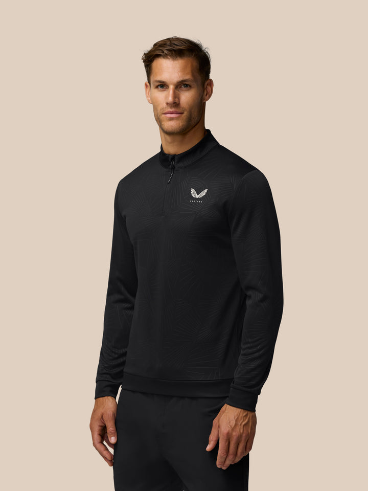 Male model wearing black Golf Club Classic 1/4 Zip Debossed Top with all over print and Castore logo on chest