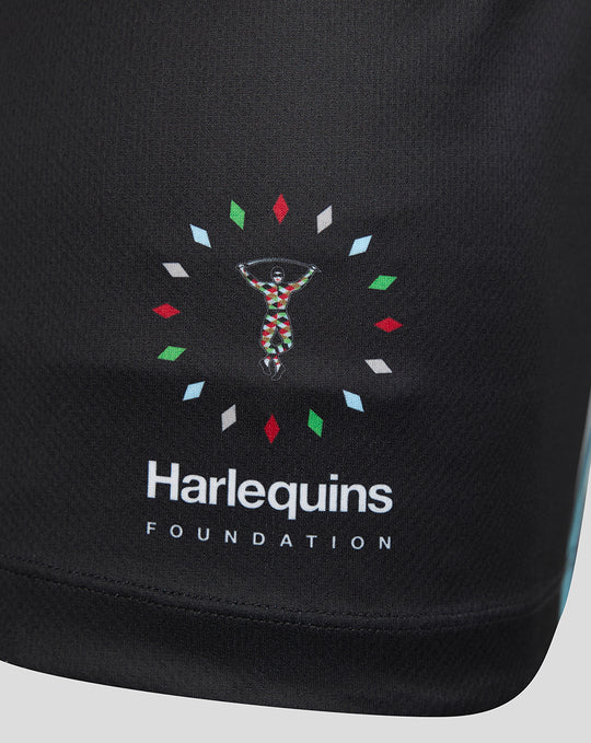 Close-up of Harlequins Foundation logo on black fabric with a colorful circular motif.