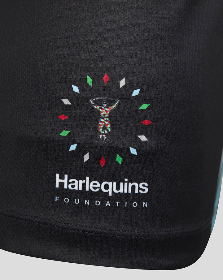 Close-up of Harlequins Foundation logo on black fabric with a colorful circular motif.