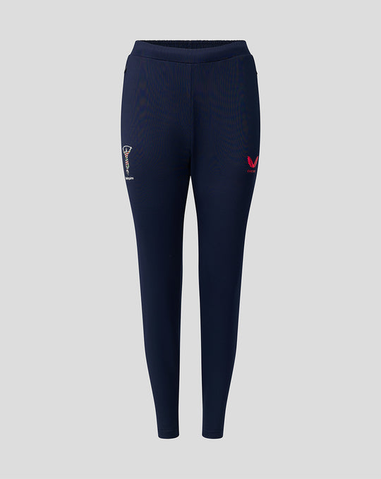 Front view of navy training track pants featuring Harlequins crest on one thigh and pink Castore wing logo on the other.