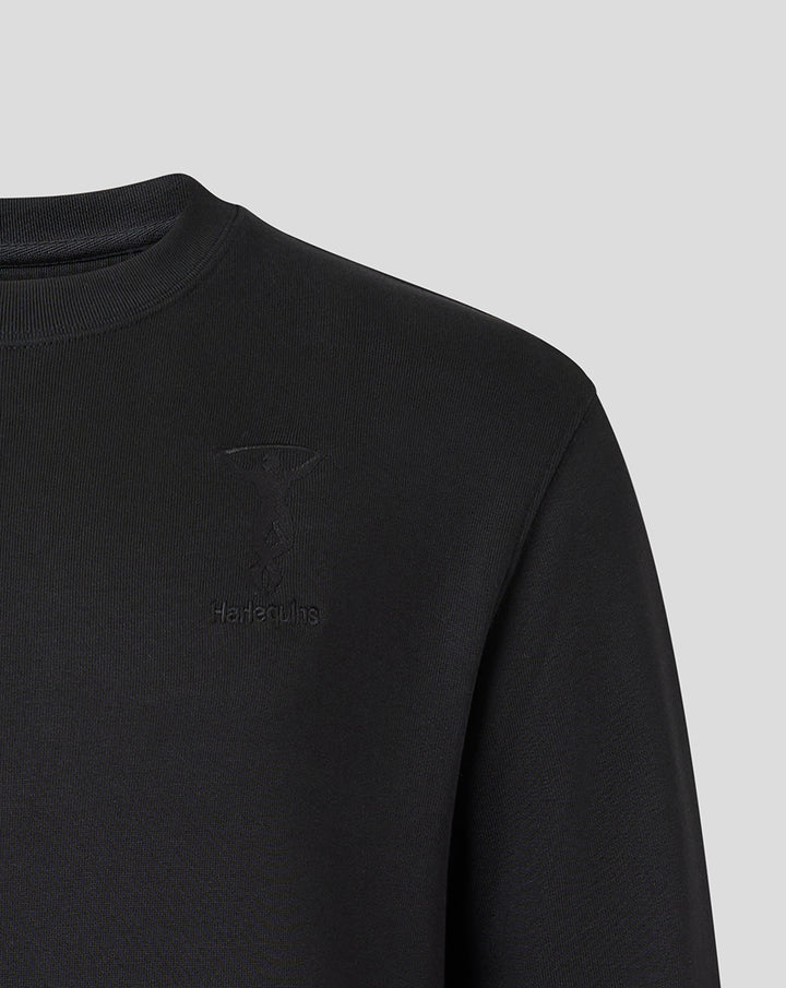 Close up of black Harlequins crew neck sweatshirt with tonal crest embroidery and Castore branding on the chest.