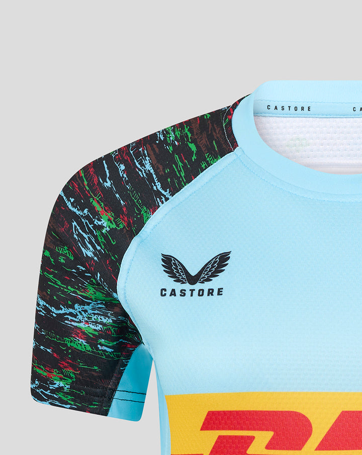 Shoulder close-up of light blue jersey showing multicolor sleeve pattern and Castore branding near the neckline.