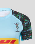 Close-up of chest displaying Harlequins crest on light blue jersey with colorful patterned sleeve.