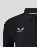 Close-up of a black travel polo showing the winged Castore logo on the chest
