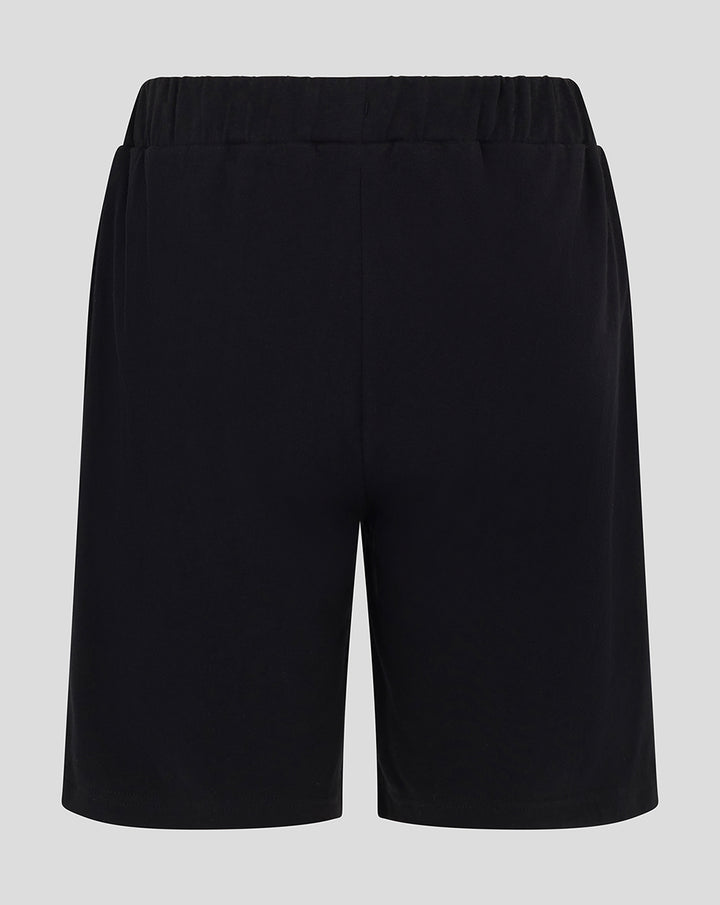 Back view of youth black shorts with elastic waistband and Harlequins crest on the lower left hem
