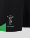 Close-up of black Harlequins home shorts with multicolored club logo and green trim.