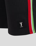 Close up of black shorts with Harlequins patch near the hem and a bold vertical green red white side stripe.