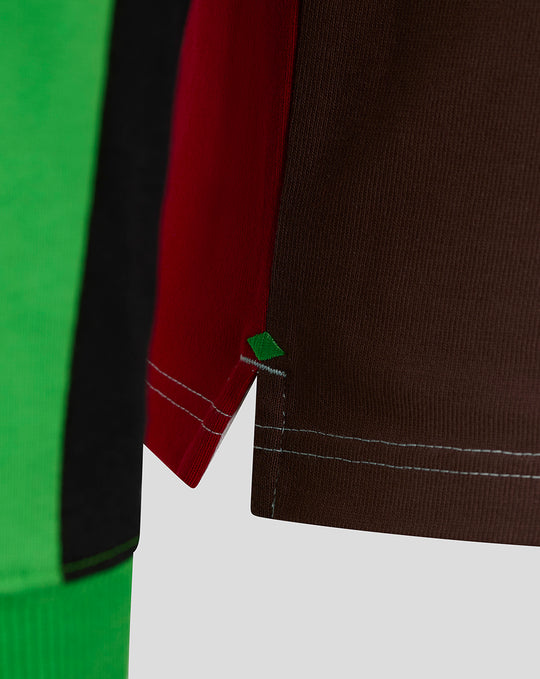 Close up of color blocked rugby shirt sleeve with red brown green panels and a small green diamond patch.