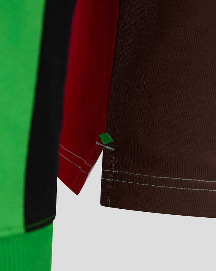 Close up of color blocked rugby shirt sleeve with red brown green panels and a small green diamond patch.