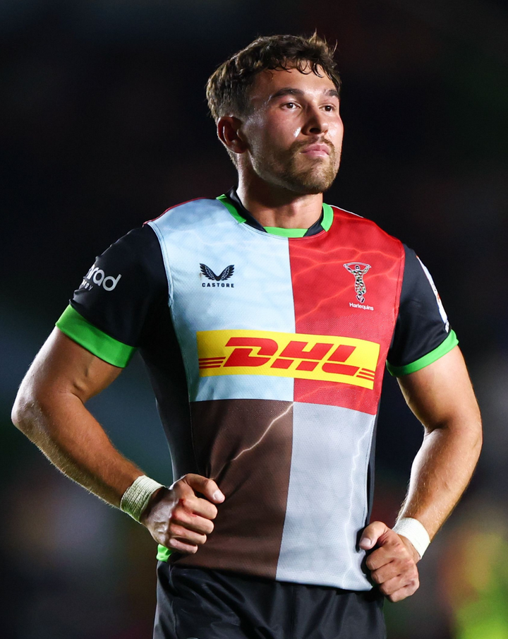 Rugby player wearing the Harlequins Home Replica Shirt on the field displaying the patchwork design and DHL sponsor